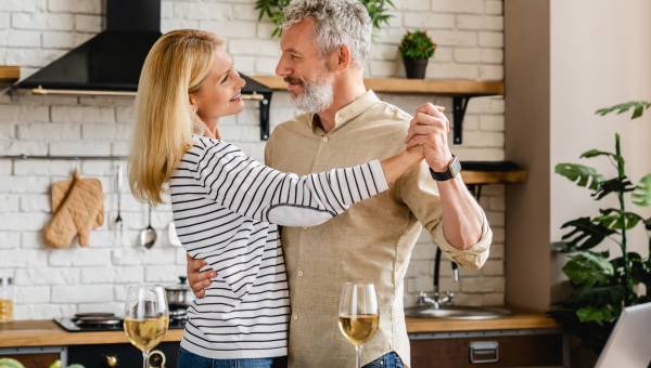 Middle aged couple dancing at home kitchen