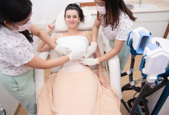 Two technicians preparing a woman for a CoolSculpting session in a comfortable clinic setting.