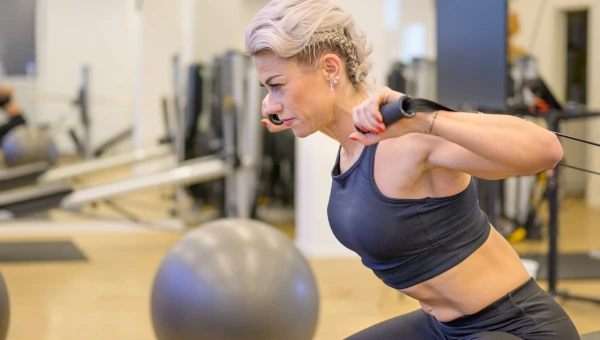 Woman performing resistance training in a gym for hormonal health