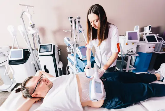 Technician performing CoolSculpting on a man's abdomen in a clinic with advanced equipment.