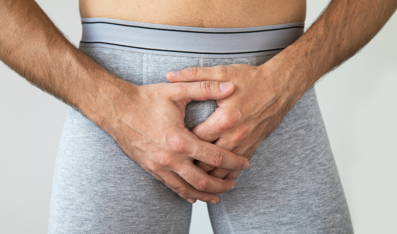 Man in gray underwear holding groin area