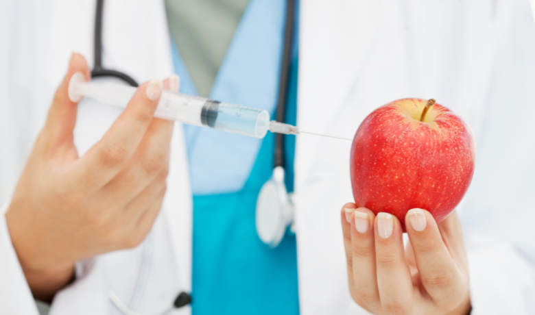 Doctor injecting apple with syringe representing cosmetic treatment