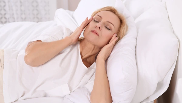 Woman lying in bed massaging her temples to relieve stress